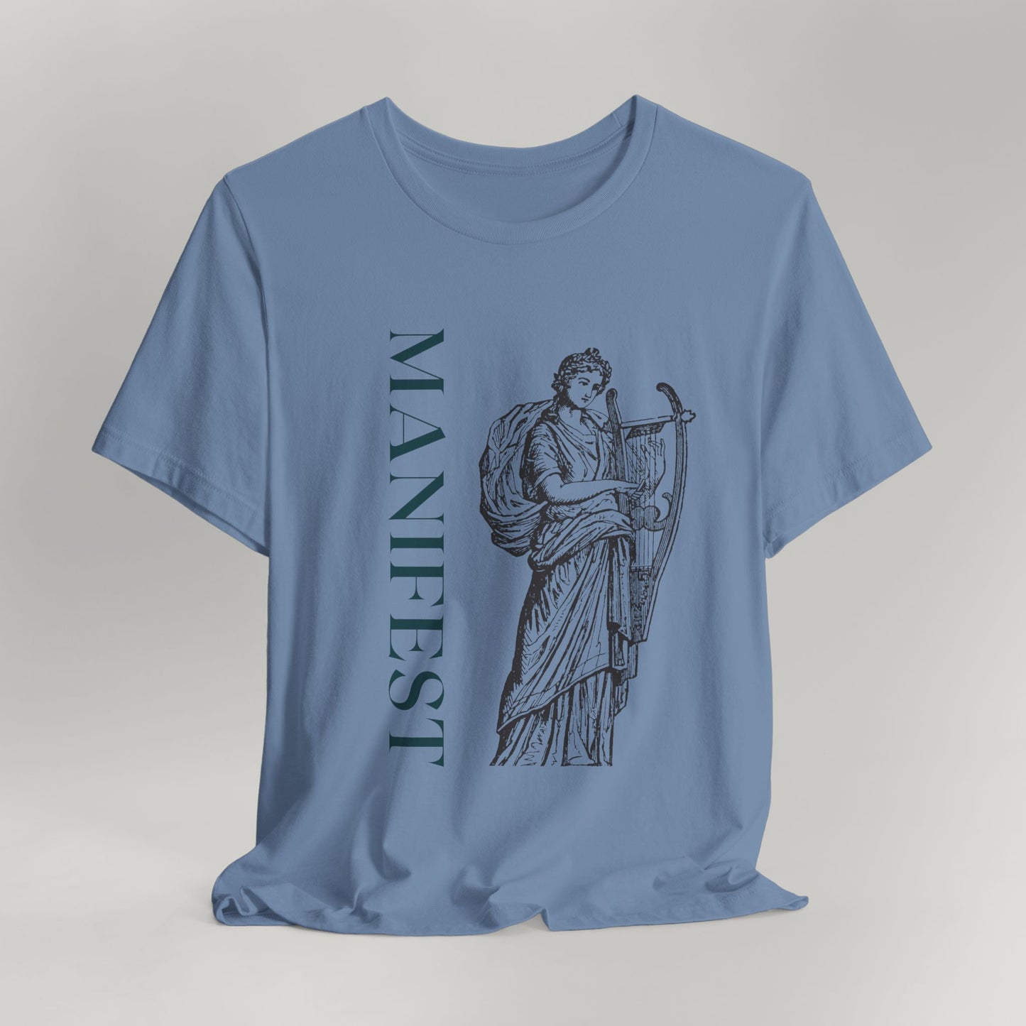 Blue t-shirt with a graphic design and the word 'MANIFEST' on a gray background